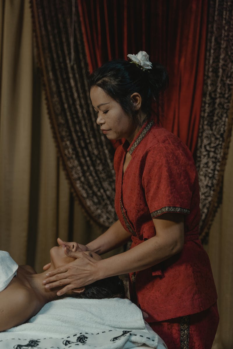A calming spa treatment featuring a masseuse providing a soothing facial massage indoors.
