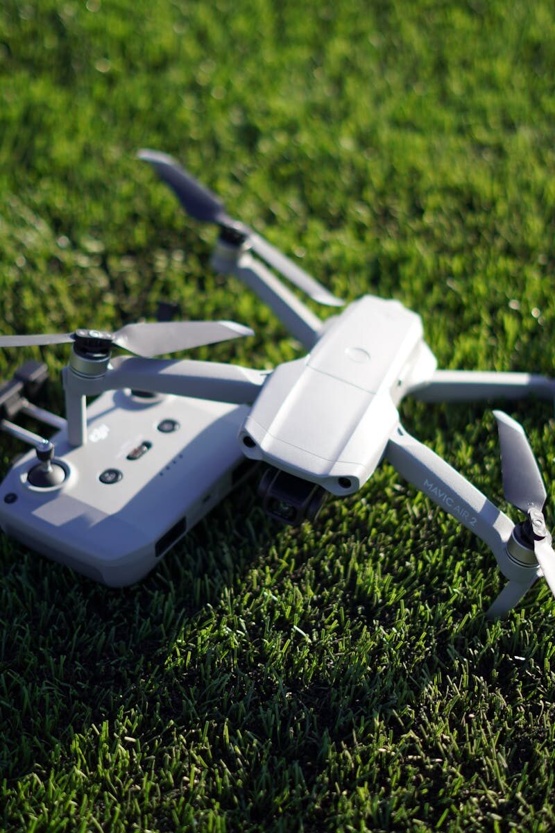 A detailed shot of a drone with controller on a lush green grass field.